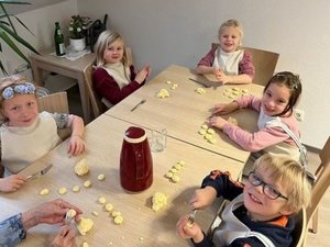 Kinder formen Plätzchen sitzend am Tisch