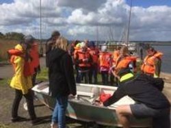 Kinder in orangenen Warnwesten am Boot