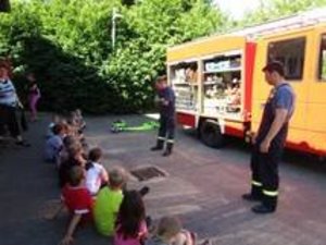 Kinder sitzen vor einem Feuerwehrauto